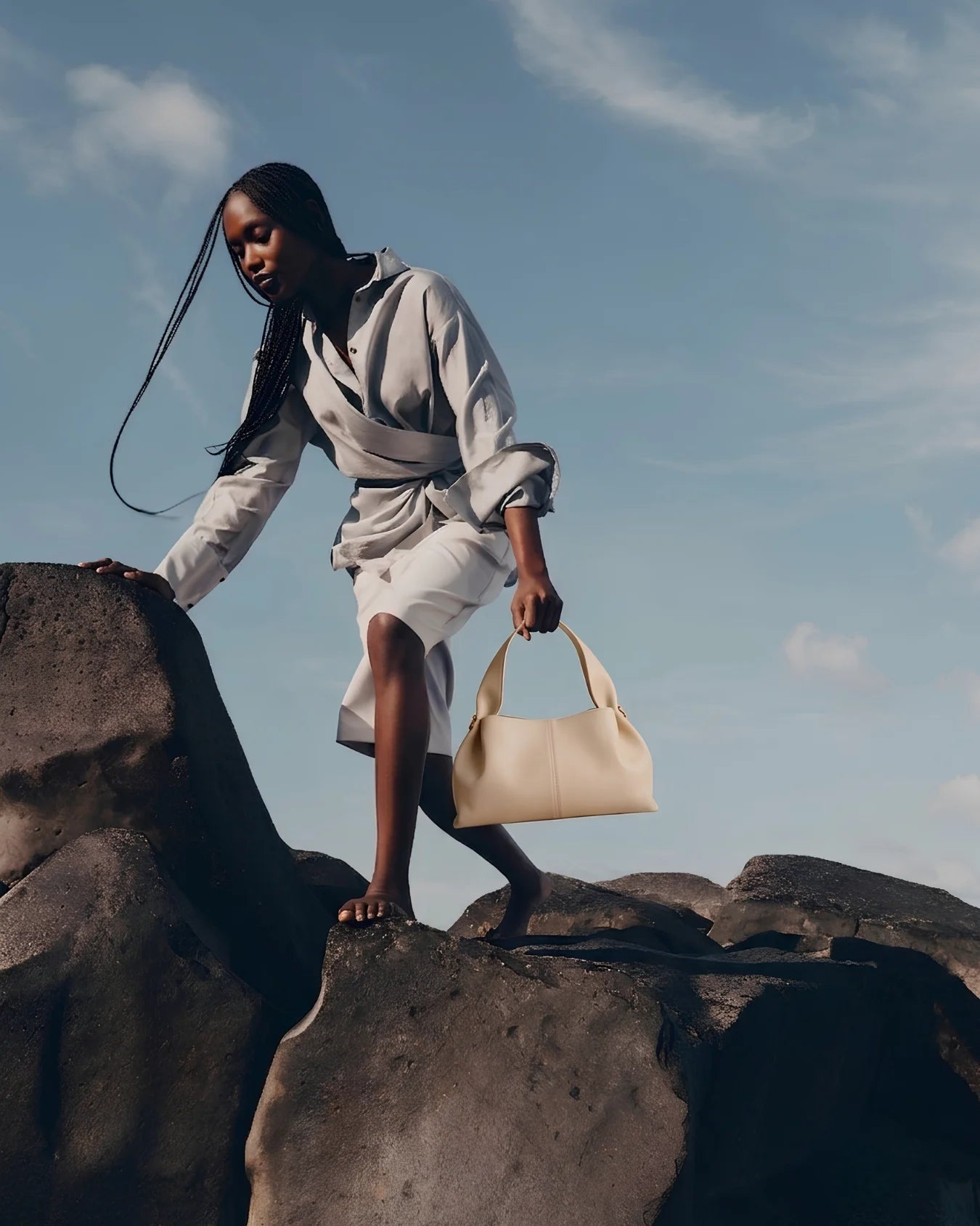 Woman on rocky terrain holding a beige leather handbag in Pakistan - The Haven Collection by My Light