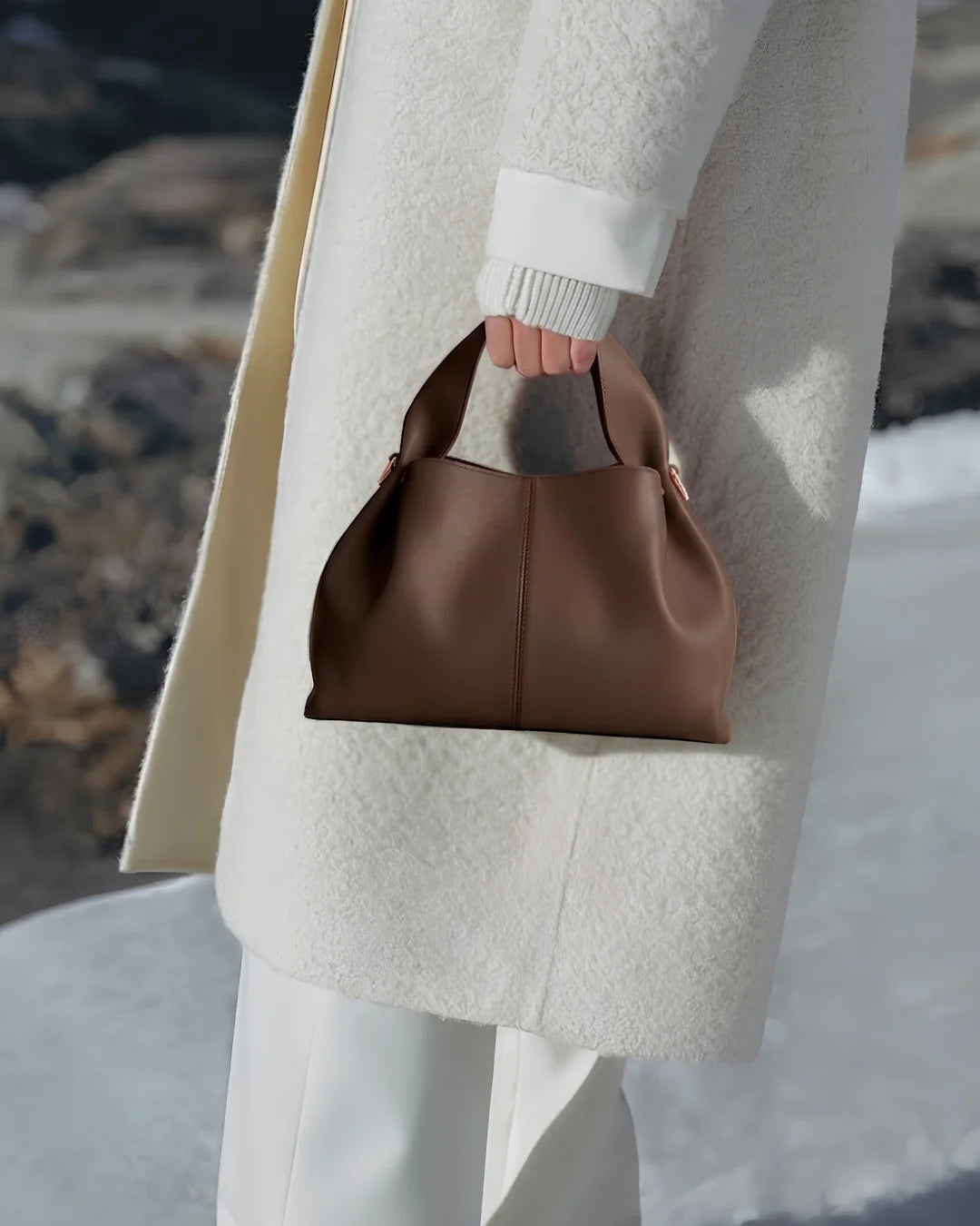 Woman in a white coat holding a brown leather handbag in Pakistan - The Haven Collection by My Light
